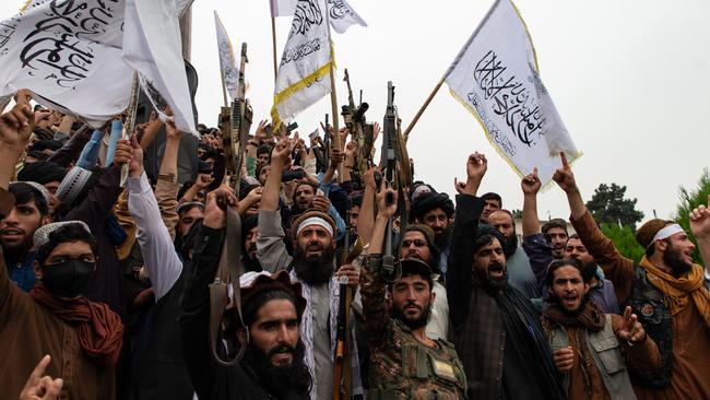 Men wave the flag of the Islamic Emirate of Afghanistan during a celebration of the first anniversary of the Taliban's return to power on August 15 in Kabul.