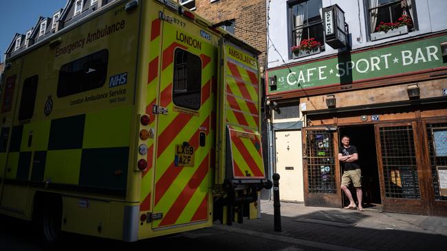 An ambulance drives past as Gareth Kerr, the owner of Cafe Kick, stands in the doorway of his closed sports bar in London. Picture: Getty Images