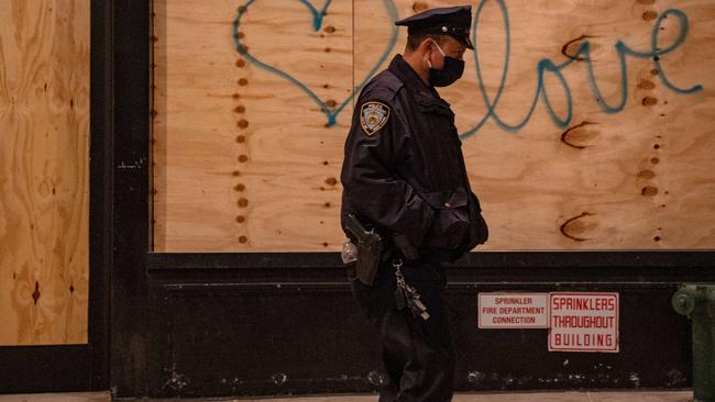 A police officer walks by graffiti on a boarded-up business in New York City the day after the election. Picture: David Dee Delgado/Getty Images