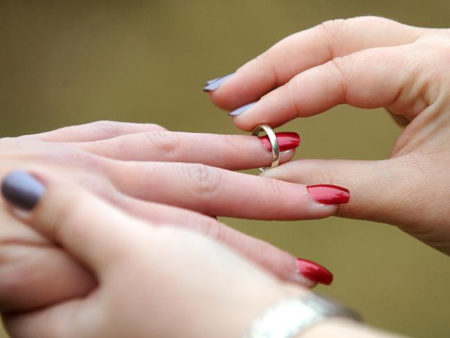 A woman places a wedding ring on her partners finger in Canberra, Monday, May 27, 2013. Australian Greens MP Adam Bandt will introduce a same sex marriage bill into parliament next week. (AAP Image/Alan Porritt) NO ARCHIVING