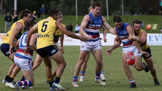 Central District’s Isaya McKenzie tries to get his kick away under pressure against Woodville-West Torrens. Picture: AAP/Emma Brasier