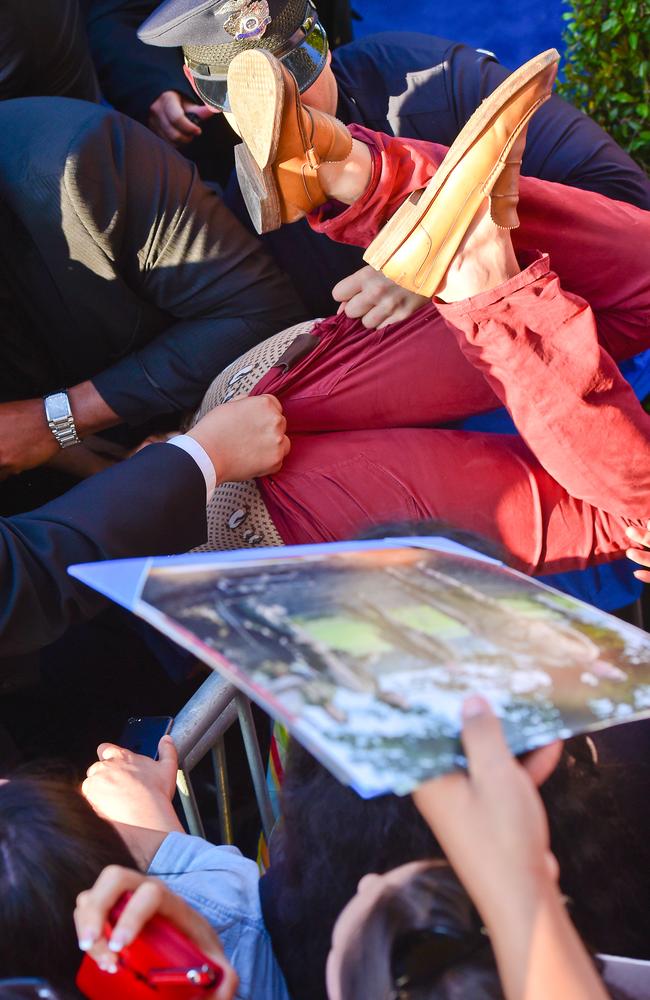 Police wrestle with a man who tried to jump the barrier at the Maleficent premiere.
