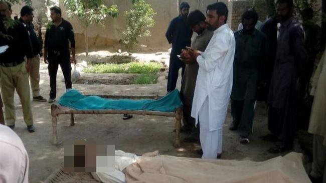 Pakistani police stand around the bodies of a woman and her alleged boyfriend who were hanged to death by the woman’s father, brother and husband in the village of Chak.