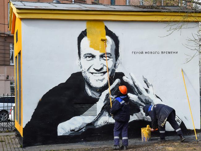 A worker paints over graffiti of jailed Kremlin critic Alexei Navalny in Saint Petersburg. The inscription reads: "The hero of the new times". Picture: AFP