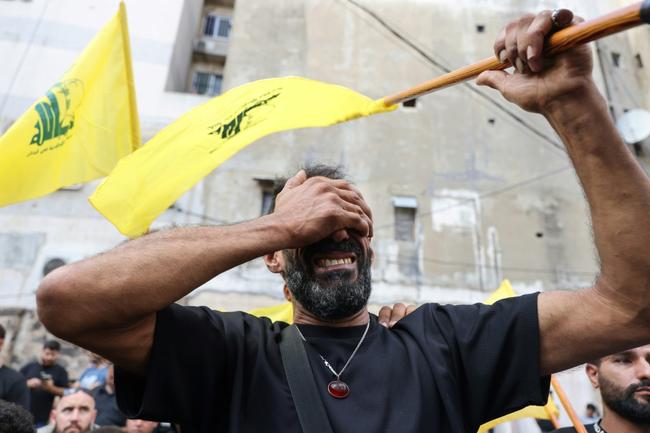 A Lebanese man with a Hezbollah flag at a funeral for people killed in by the pager explosions