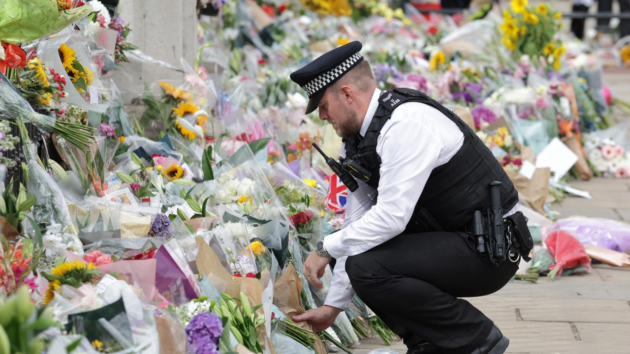 A police office places flowers at Buckingham Palace. Picture: Getty