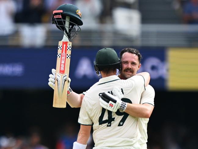 BRISBANE, AUSTRALIA - DECEMBER 15: Travis Head of Australia celebrates with teammate Steve Smith while raising his bat after scoring a century during day two of the Third Test match in the series between Australia and India at The Gabba on December 15, 2024 in Brisbane, Australia. (Photo by Bradley Kanaris/Getty Images)