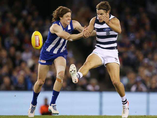 Geelong’s Jake Kolodjashnij gets a kick away as fellow Tasmanian Ben Brown, of the Kangaroos, arrives. Picture: MICHAEL KLEIN