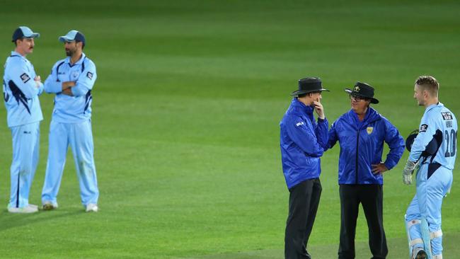 Umpires Phillip Gillespie and John Ward talk to Blues captain Peter Nevill.