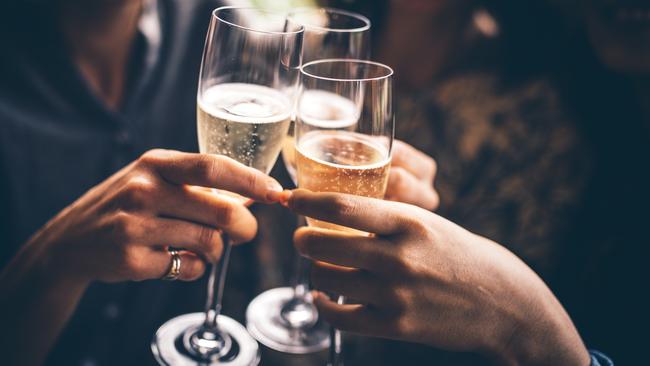 Three female friends celebrating with champagne. They are sitting in a bar and toasting with glasses of champagne.