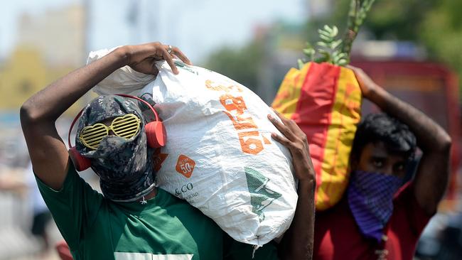 A man with his face covered amid fears of the spread of the COVID-19 novel coronavirus, carries a sack of vegetables near a market during a government-imposed nationwide lockdown as a preventive measure against the COVID-19 coronavirus in Chennai, India.