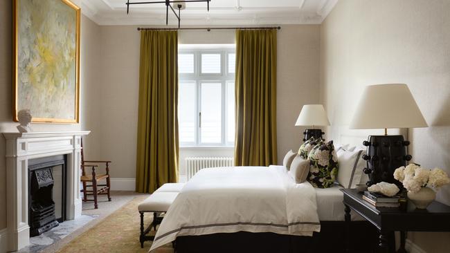 The grandeur of this bedroom enhanced by the floor-to-ceiling antique bronze silk curtains and muted tonal rug.