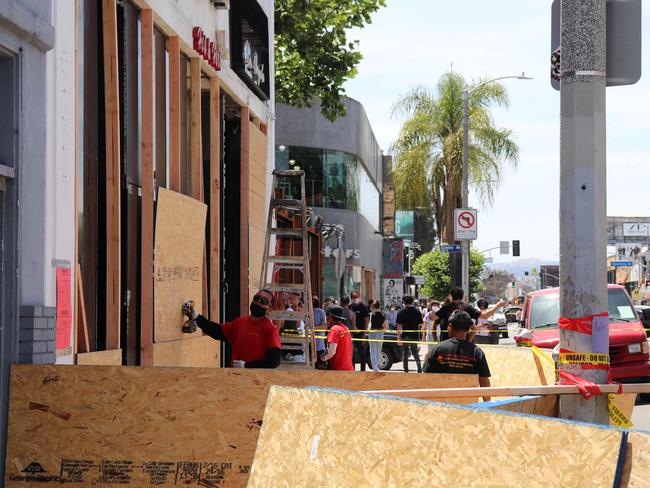 Store owners board up their stores that were looted after a night of riots in the Merlose area of Los Angeles.