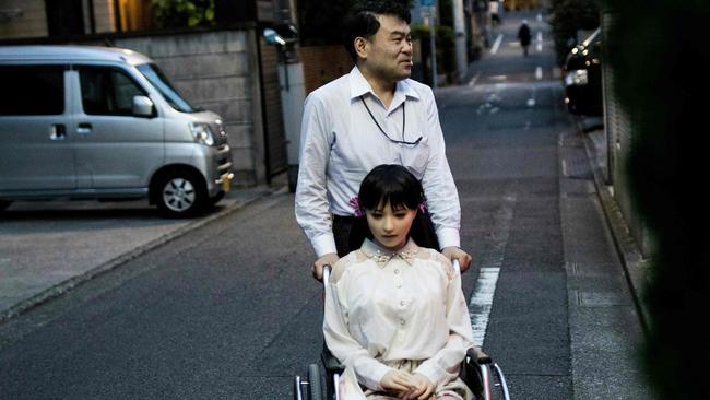 Masayuki Ozaki stands with his silicone sex doll Mayu outside his apartment in Tokyo. Picture: AFP.