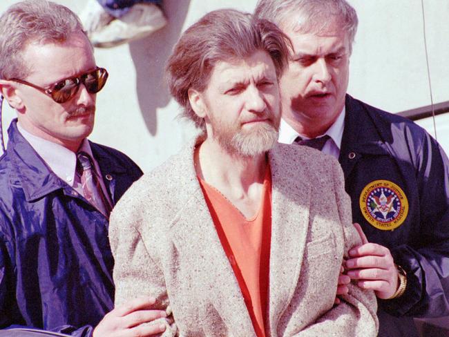 Ted Kaczynski is flanked by federal agents as he is led to a car from the federal courthouse in Helena, Montana in April 1996. Picture: AP