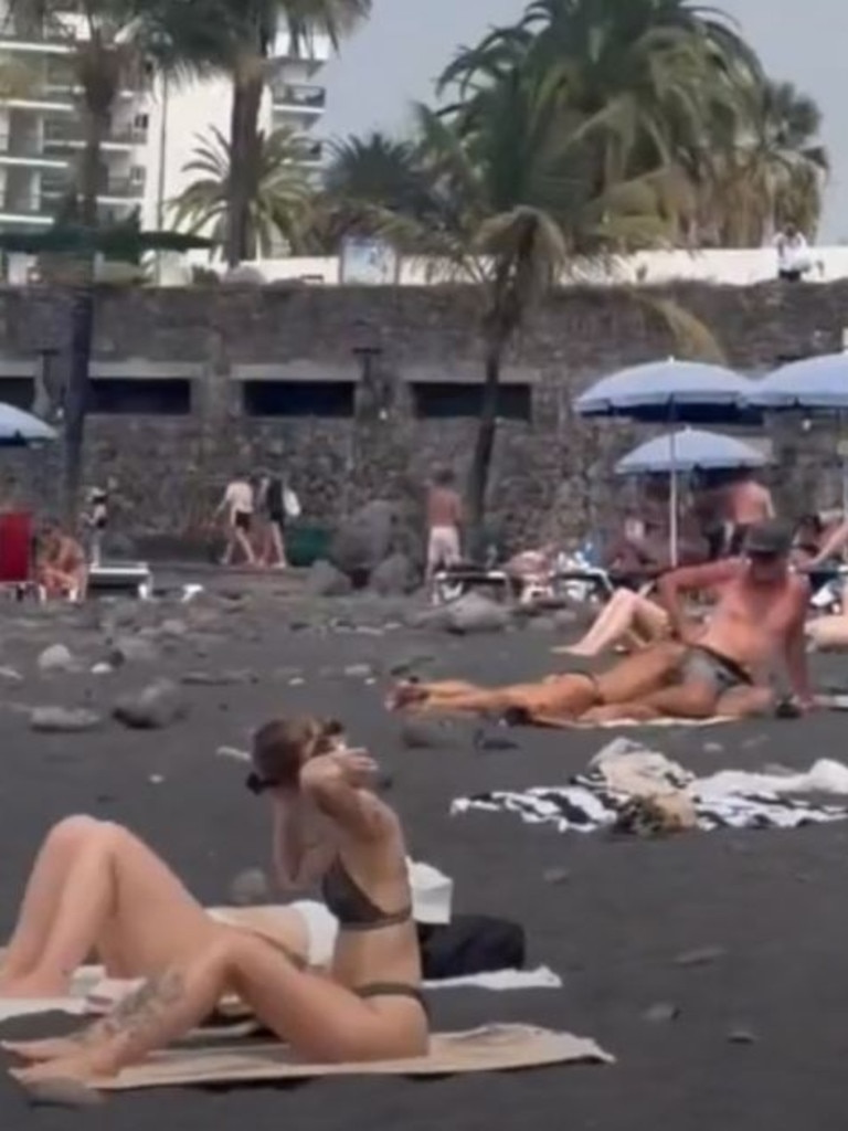 Beachgoers in Tenerife lay in the sun as the fire burns. Picture: @neftis26 via Storyful