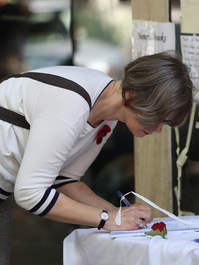 A woman signs a condolence book for the Bourke street tragedy in front of Pellegrini cafe. Picture: David Crosling