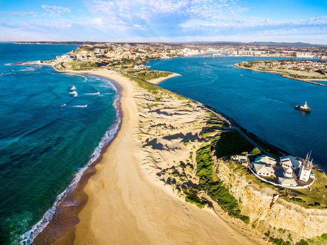 A man sits overlooking a panoramic view of a beautiful coastline near Newcastle, Australia.