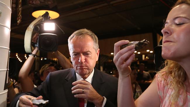 SHELLING OUT PROMISES: Opposition Leader Bill Shorten and Labor candidate for Boothby Nadia Clancy down Coffin Bay oysters from Manuel’s seafood at Westfield Marion on Tuesday. Picture Kym Smith