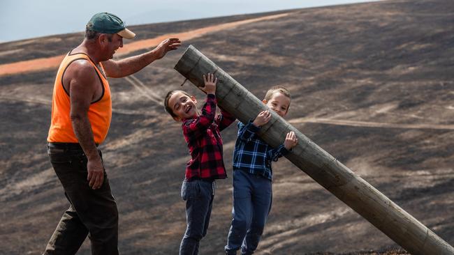 Russell Foster with his twin 7-year-old sons, Jayden and Rhys, on their Omeo farm as the rebuild begins after a fire razed 600 acres of their land. Picture: Jason Edwards