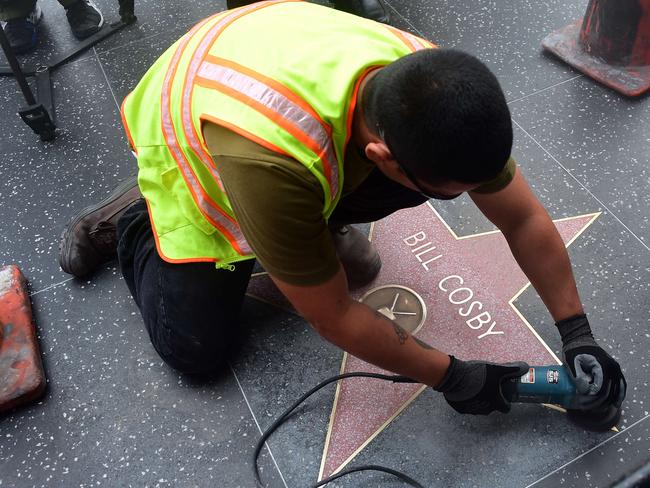 Reputation tarnished ... a worker cleans Bill Cosby's Star on the Hollywood Walk of Fame on December 5. Picture: AFP Photo / Frederic J. Brown