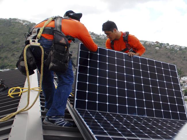 FILE - In this July 8, 2016, file photo, Radford Takashima, left, installer for RevoluSun, and lead installer Dane Hew Len, right, place solar panels on a roof in Honolulu. If you have the cash, most experts agree buying a solar system outright is a better investment than leasing or taking out a loan. Customers should check electric bills to estimate monthly energy use when deciding what size system to buy, and calculate federal or state incentives. (AP Photo/Cathy Bussewitz, File)