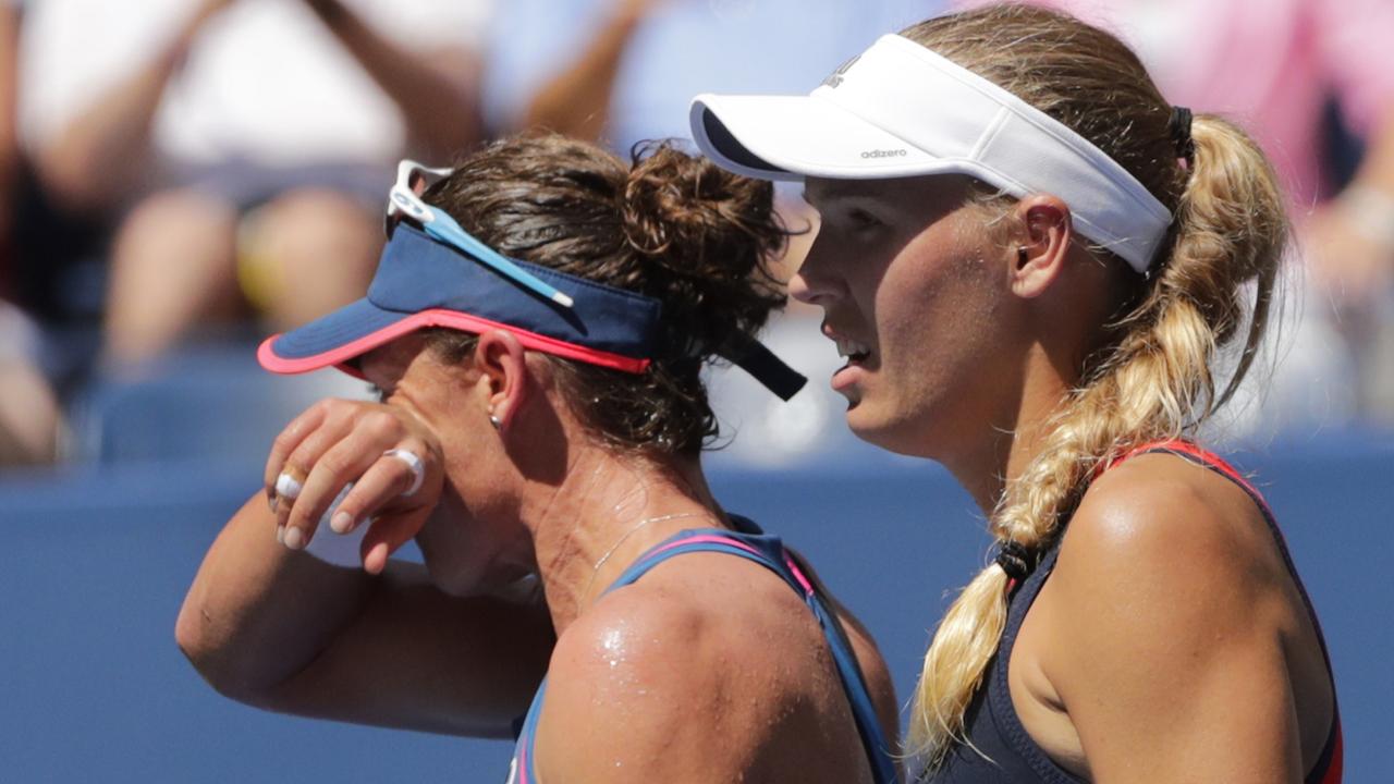 Caroline Wozniacki, right, of Denmark, looks on as Samantha Stosur, of Australia, wipes her face.