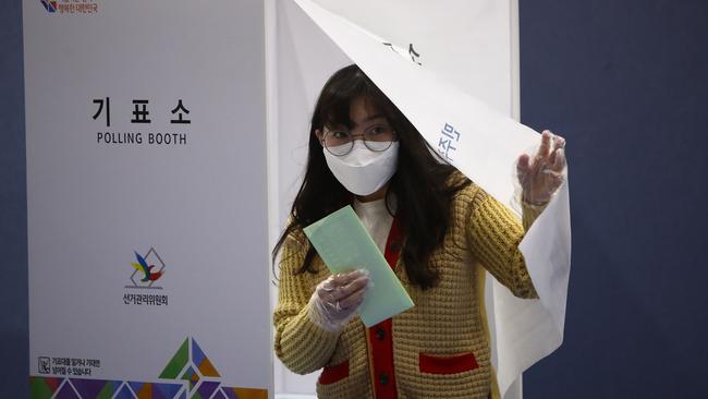 A South Korean woman wearing a mask and plastic gloves casts her vote in a polling station on the Parliamentary election amid the coronavirus outbreak in Seoul, South Korea. Picture: Getty Images