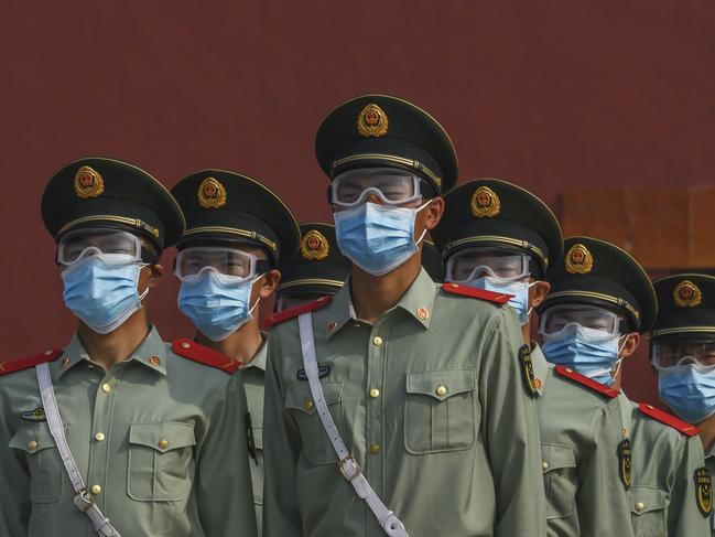 Chinese paramilitary police wear protective masks as they guard the entrance to Beijing’s Forbidden City. Picture: Getty Images