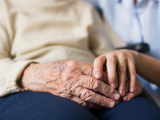 Unrecognizable senior woman in wheelchair with a health visitor at home at Christmas time.