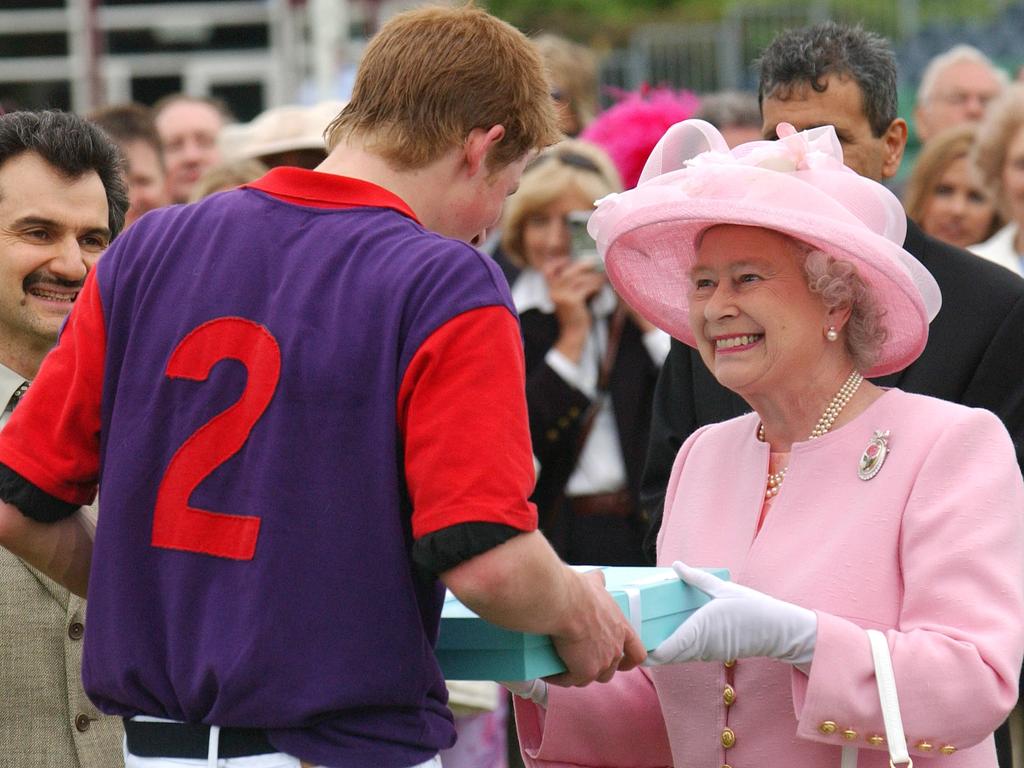 The Queen presents grandson Prince Harry with a gift at a polo event in Windsor. Picture: Mark Cuthbert/UK Press via Getty Images