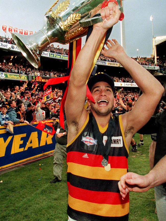 Crows legend Andrew McLeod wearing the Norm Smith Medal and holding AFL premiership cup trophy after the 1998 grand final win.