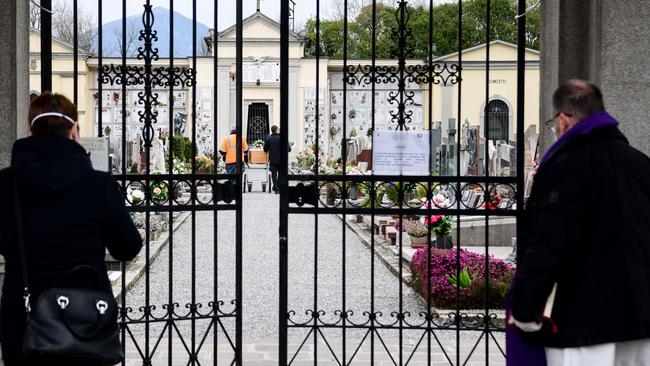 A mourner and a priest wait for a coffin at a cemetery in Bolgare, Lombardy, on Monday. Picture: AFP