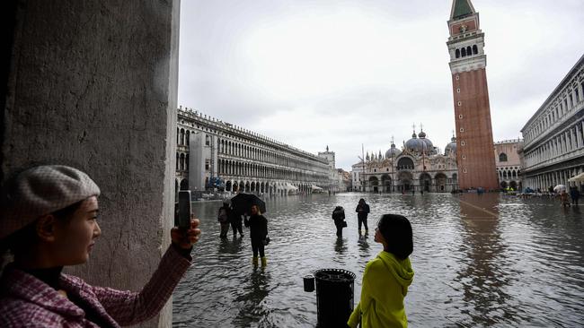 Tourists take photos at the flooded St Mark's Square. Picture: AFP