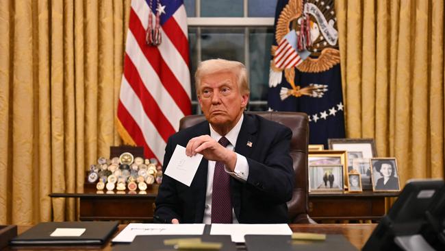 Family portraits of Fred and Mary Trump are visible as US President Donald Trump signs his executive orders. Picture: AFP