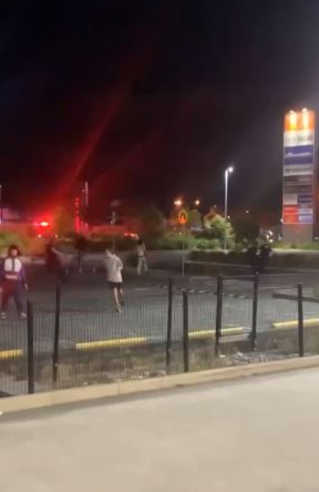 Police chase down a man at the hooning rally in Robina on Saturday night.