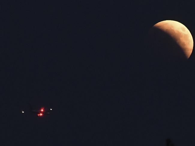 A plane flies near the moon during a 'blood moon' eclipse in Rome. Picture: AFP