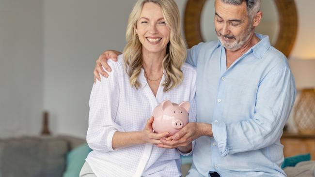 Mature Couple holding a piggy bank in their new home. Home savings concept. Both are happy and smiling. money generic