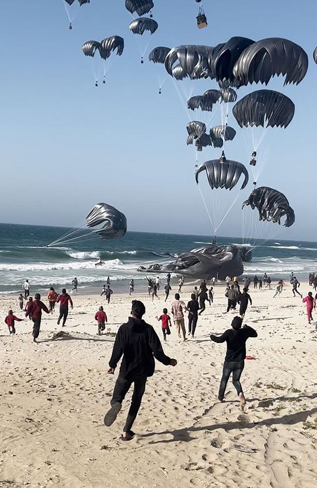 Palestinians rush to collect food parcels air-dropped by US aircraft on a Gaza Strip beach, amid reports of child malnutrition deaths. Picture: AFP