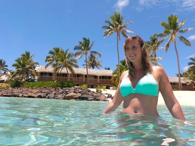 LOW ANGLE, CLOSE UP: Joyful young woman in turquoise bikini looking around the tropical seascape of Cook Islands. Girl on summer holiday relaxing in refreshing ocean near the sunny white sand beach.