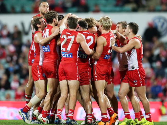 Lewis Melican of the Swans celebrates with team mates after kicking a goal.