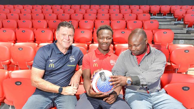 Adelaide United coach Carl Veart, left, teenage superstar Nestory Irankunda and his dad Gideon at Coopers Stadium after his signing. Picture: Newswire / Brenton Edwards