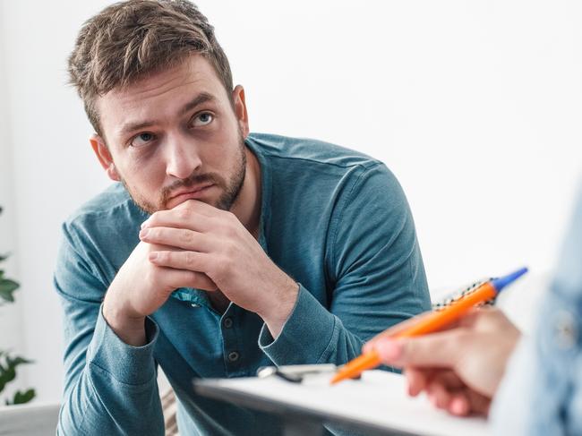 Man with psychologist drug addiction problems concept sitting on sofa looking at doctor taking notes close-up