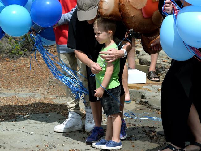 Missing fisherman Jesse Howes' two year old son Chaise is comforted by Jesse's brother Sam and his mum Kaila Walker just before they let the tribute balloons go at the scene of the tragic accident. Picture: Peter Lorimer