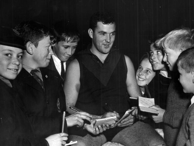 Melbourne's Neil Crompton signing autographs for young supporters in the dressing rooms.