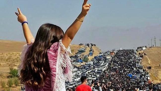 An unveiled woman stands on top of a vehicle as thousands march towards Mahsa Amini's home to mark 40 days since her death.