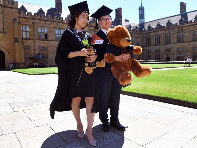 Students from China pose for family photos after graduating from a course in commerce at Sydney University.