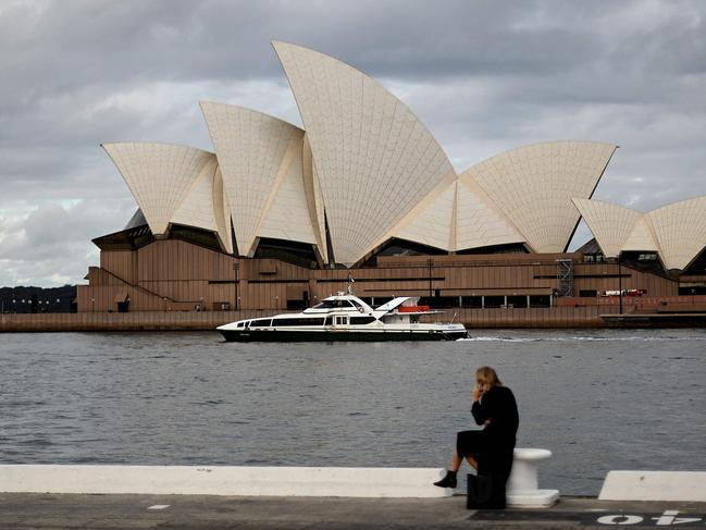 A woman talks on her phone in front of the Opera House, usually packed with locals and tourists but now quiet as international travel restrictions still in place due to COVID-19 coronavirus concerns, in Sydney on June 15, 2021. (Photo by Saeed KHAN / AFP)