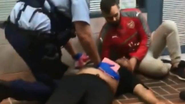 Police and a by-stander help the man who was stabbed when he went to the rescue of the girl. Picture: TVN