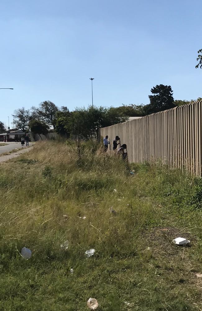 Men hold their phones inside a property to get Wi-Fi in Soweto.